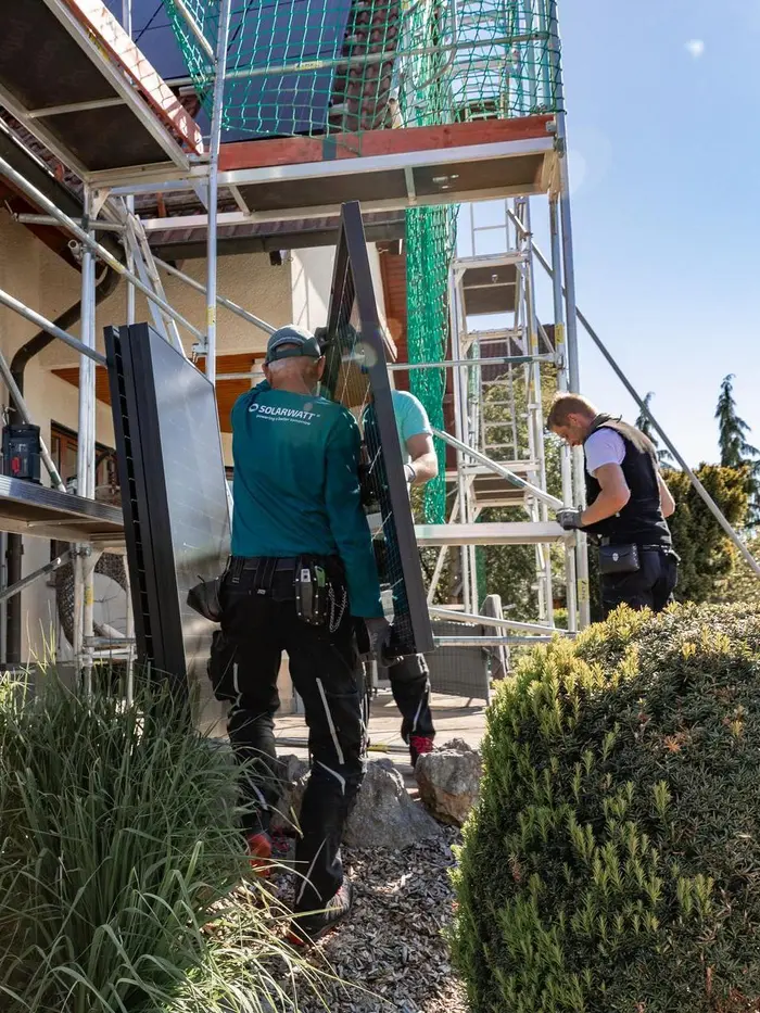 Solarwatt-Installateure tragen ein Solarmodul