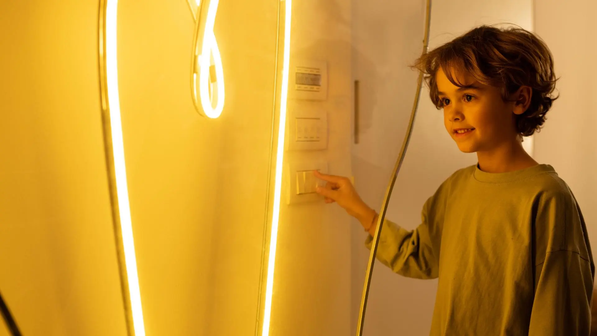 Person betätigt einen Lichtschalter neben einem beleuchteten Spiegel.