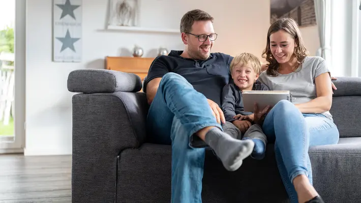 Eine Familie sitzt zusammen auf dem Sofa.