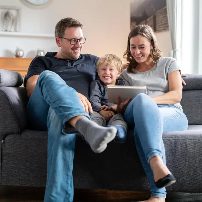 Eine Familie sitzt auf einem Sofa und schaut sich ein Buch an