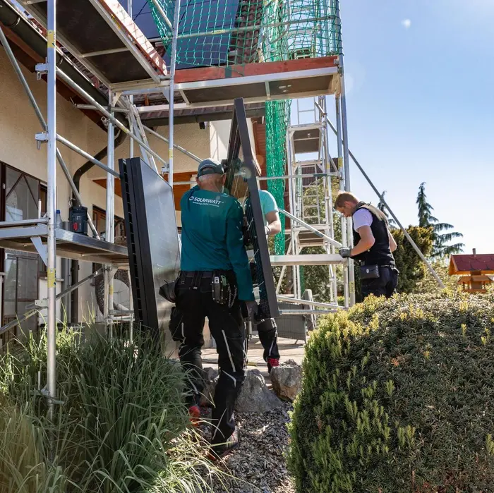 Solarwatt-Installateure tragen ein Solarmodul