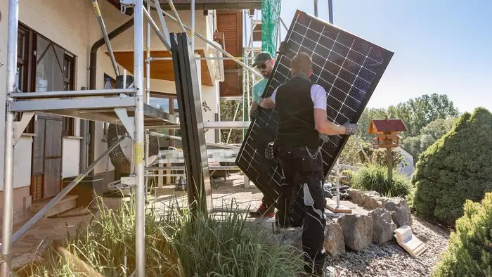 Zwei Solarwatt-Mitarbeiter installieren ein Modul auf dem Dach