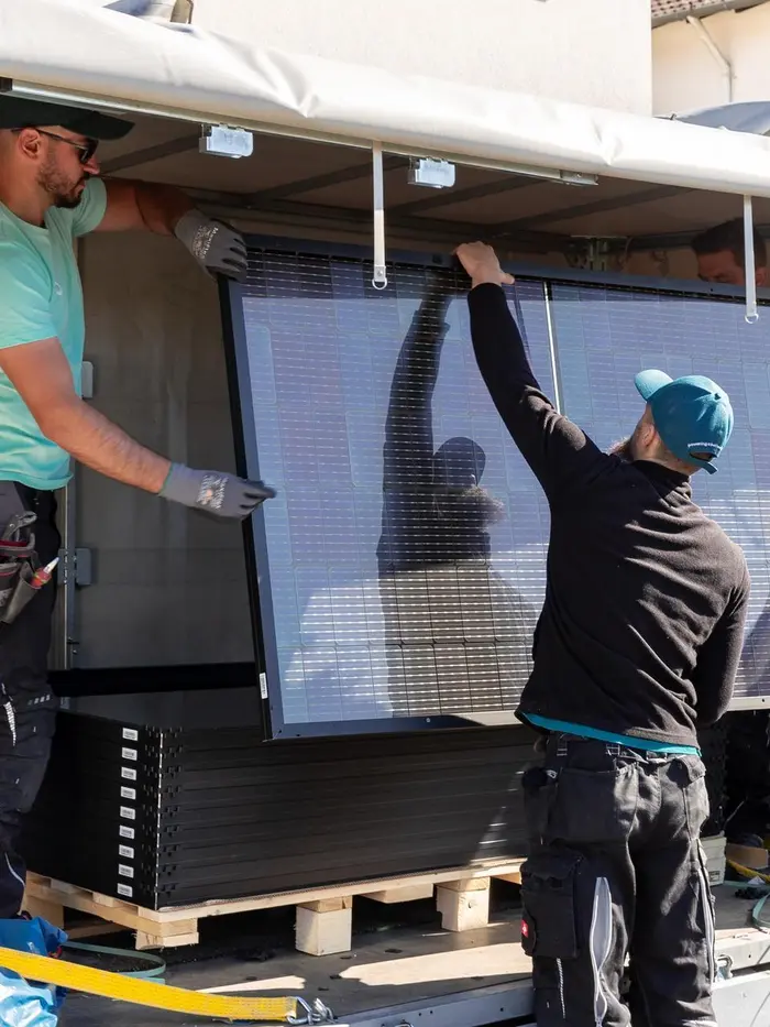 Solarwatt-Installateure laden ein Solarmodul aus
