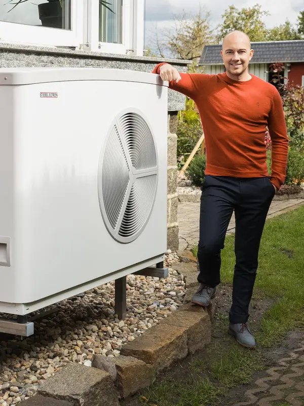 Mann steht neben Wärmepumpe