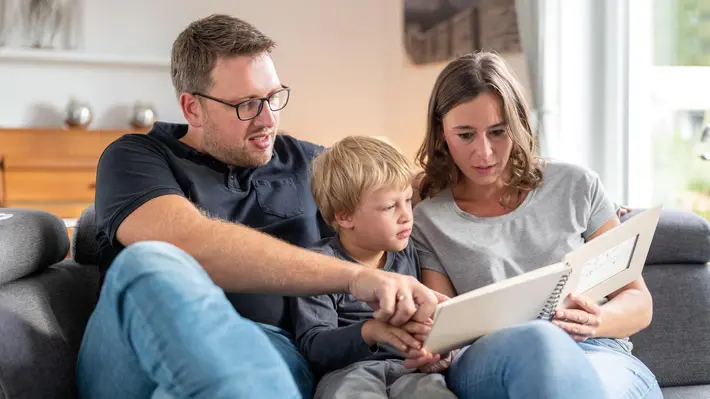 Familie mit Kind schaut sich gemeinsam ein Buch an