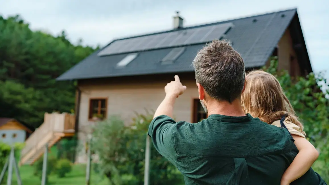 Mann mit Kind vor PV-Anlage