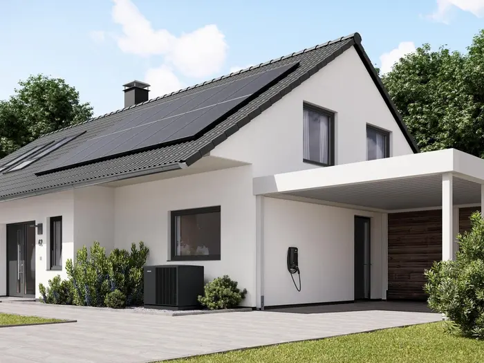 Einfamilienhaus mit Solarmodulen auf dem Dach, einer Wallbox an der Wand und einer Wärmepumpe vor dem Haus.