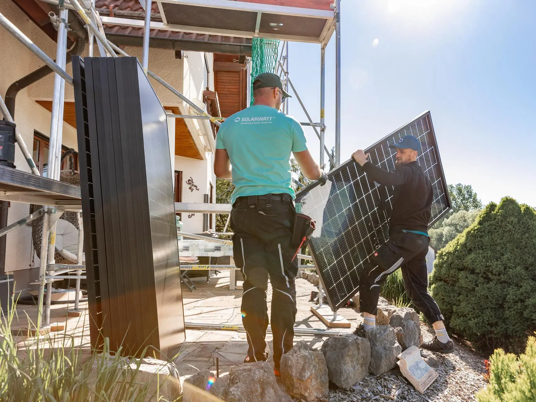 Solarwatt-Installateure tragen ein Solarmodul.