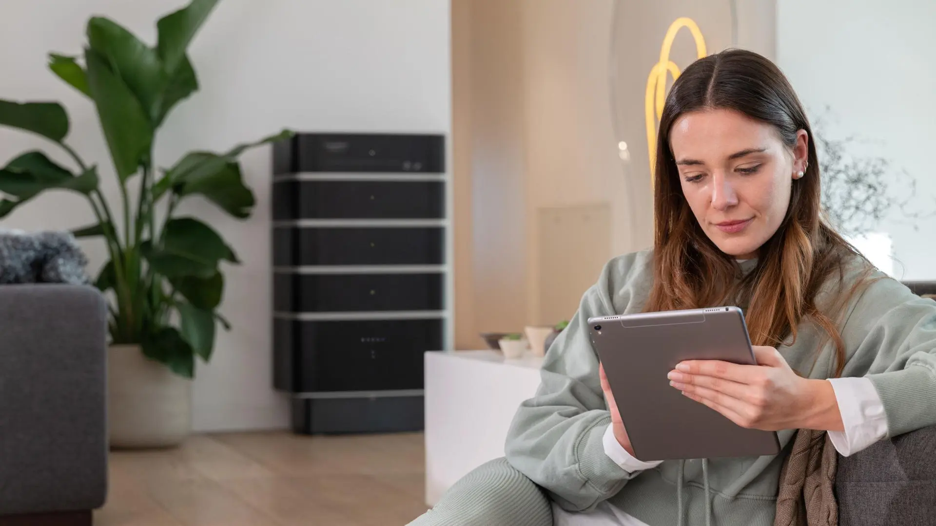 Frau arbeitet am iPad und im Hintergrund ist ein Stromspeicher zu sehen