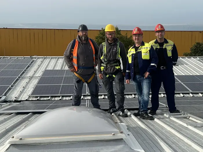 Personen auf dem Dach, auf dem eine PV-Anlage installiert ist.
