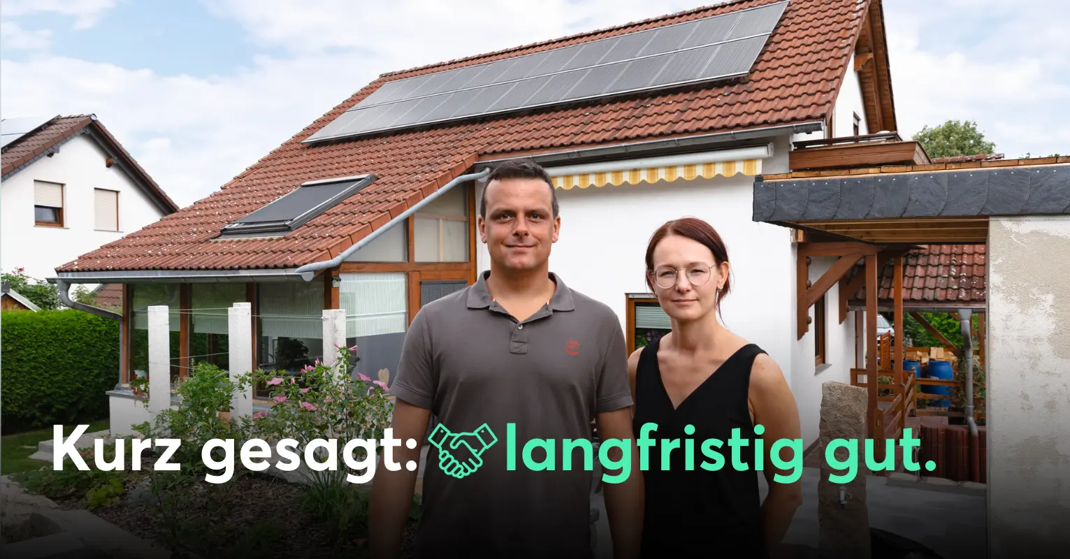 Familie steht vor Einfamilienhaus mit PV-Anlage.