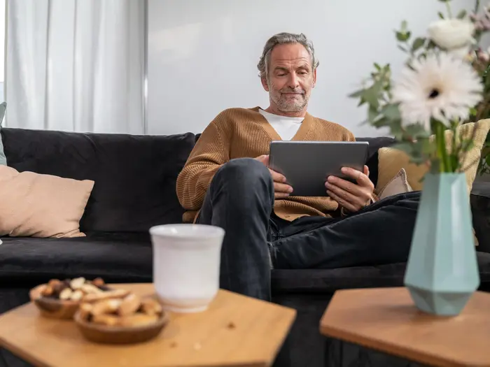 Man sits on sofa and looks at tablet