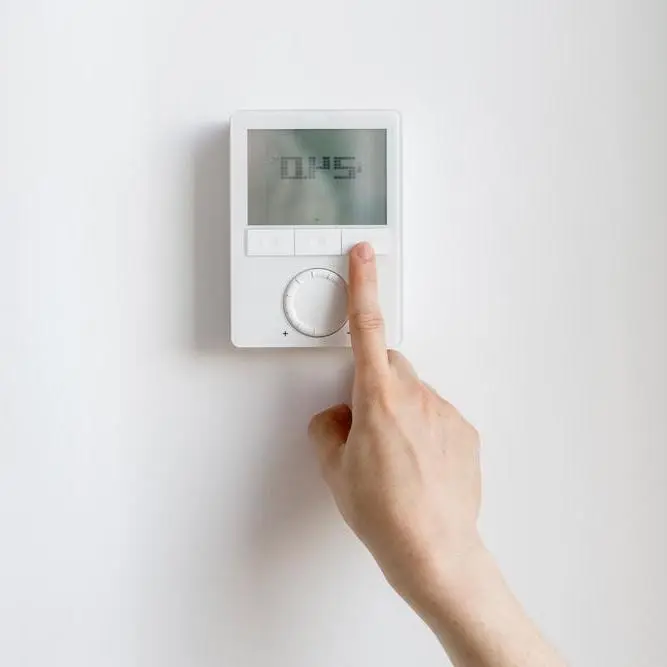 Finger zeigt auf Raumthermostat.