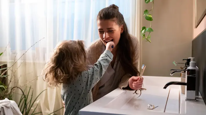 Kind putzt zusammen mit seiner Mama die Zähne
