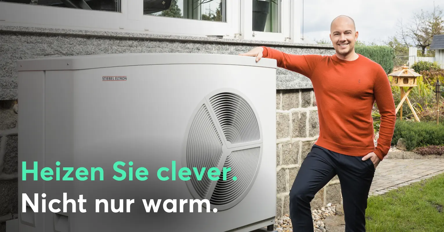 Mann steht neben Wärmepumpe.