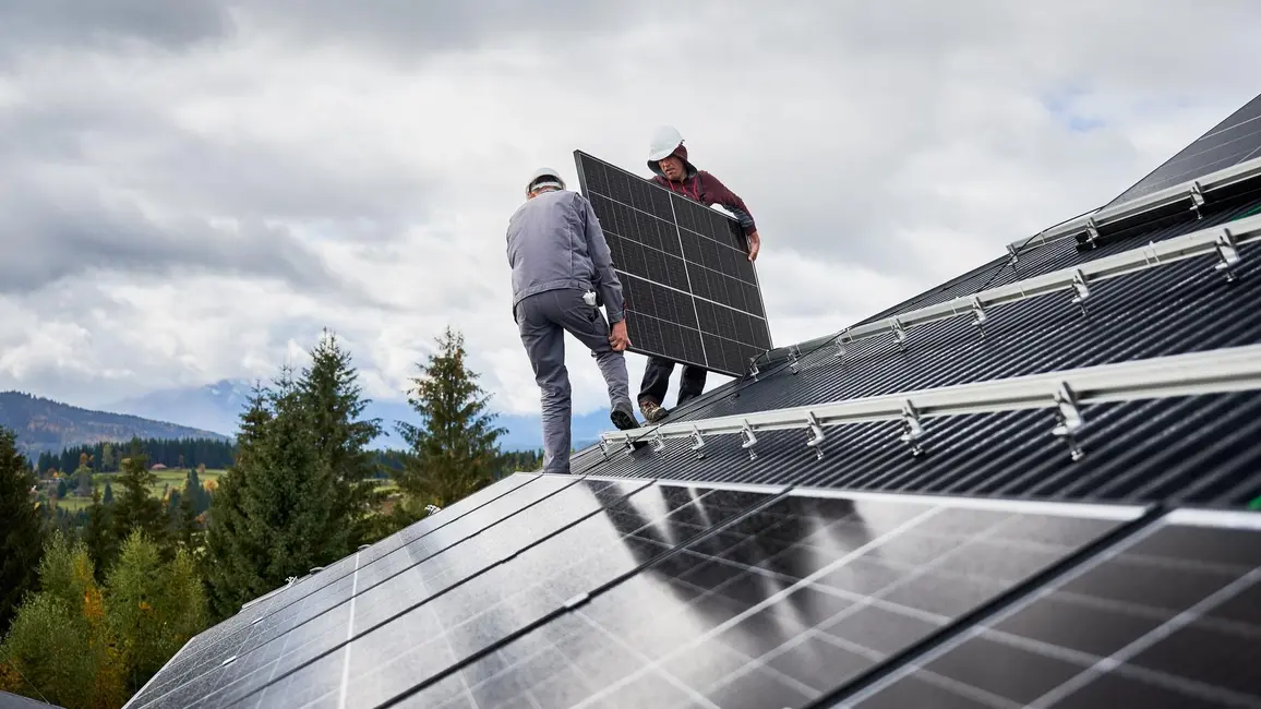 Installateure tragen zusammen ein Solarmodul