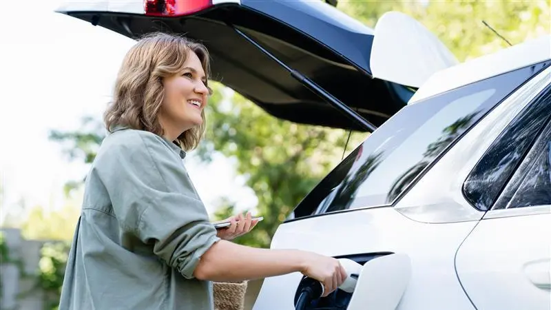 Frau lädt ihr E-Auto.