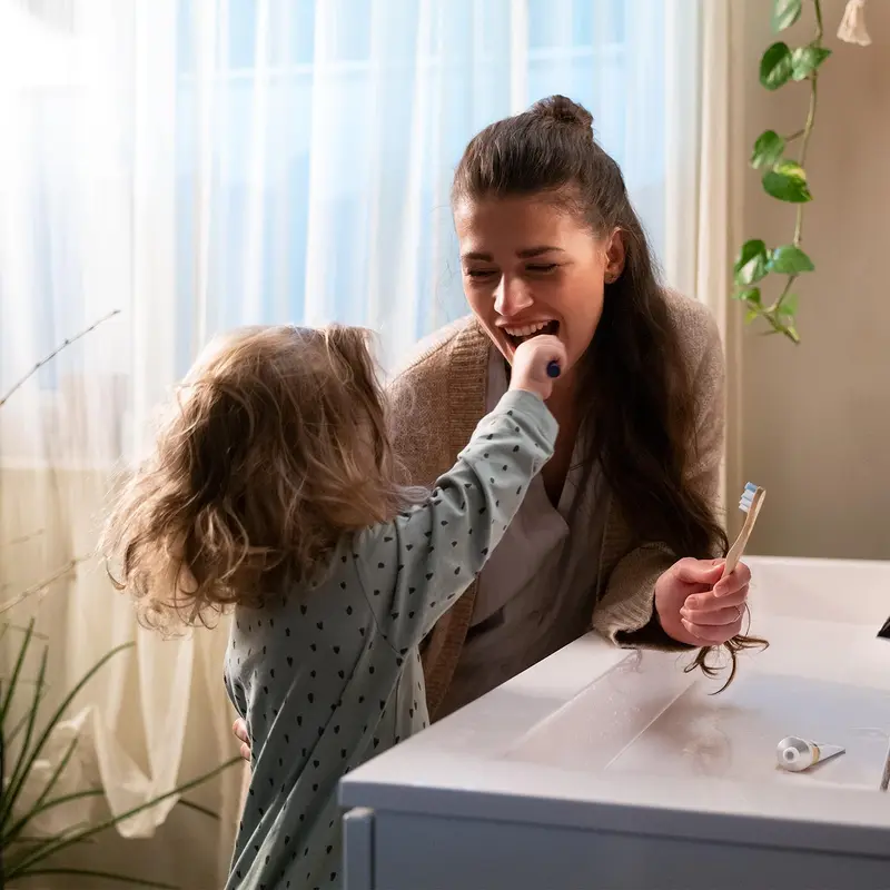 Kind putzt zusammen mit seiner Mama die Zähne