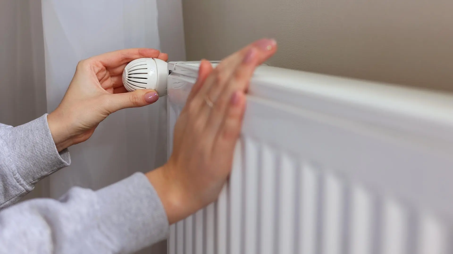 Zwei Hände an einem Heizkörper.